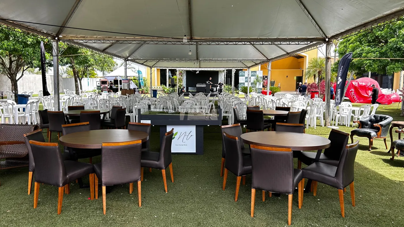 Mesas e cadeiras sob a tenda, prontas para o festival